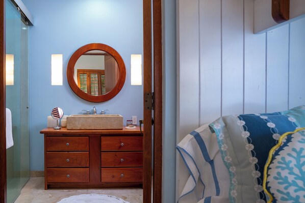 A bathroom with a wooden vanity, a round mirror, and a sink.