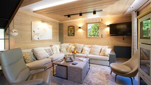 A cozy living room with a sofa set, a coffee table, and a TV mounted on the wall. - Chalet, 250m from ski lifts, sauna, terrace, balcony, fireplace or stove, tv, 130m², Les 2 Alpes (Vénosc)