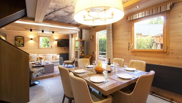 A cozy wooden interior with a dining area, a sofa, and a television. - Chalet, 250m from ski lifts, sauna, terrace, balcony, fireplace or stove, tv, 130m², Les 2 Alpes (Vénosc)