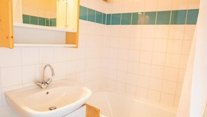 Une salle de bain avec un lavabo, un miroir et une baignoire.