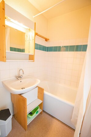 Ein Badezimmer mit Waschbecken, Spiegel und Badewanne.