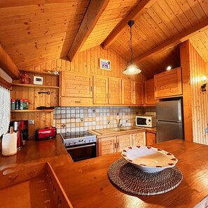 A wooden kitchen with a tiled backsplash, a microwave, a refrigerator, and wooden cabinets.