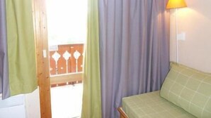 Ein Zimmer mit einem Bett, einem Vorhangfenster und einer Wandlampe.