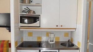 Eine kleine Küche mit Mikrowelle, Kaffeemaschine und Geschirrspüler.