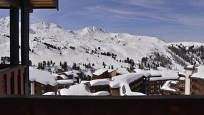 Eine verschneite Berglandschaft mit Blick auf eine Stadt mit Holzbauten.