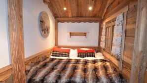 A cozy room with a wooden ceiling, a bed with a fur blanket, and a wall-mounted shelf. - 10m from ski slopes, 7th floor, tv, 24m², Les Menuires (Les Menuires)
