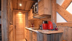 A compact kitchen with wooden walls, a built-in microwave, a red coffee maker, and a sink. - 10m from ski slopes, 7th floor, tv, 24m², Les Menuires (Les Menuires)