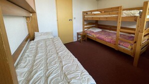 A bedroom with a single bed, a bunk bed, and a door. - 10m from ski slopes, 6th floor, view valley, balcony, tv, 18m², Les Menuires (Les Menuires)