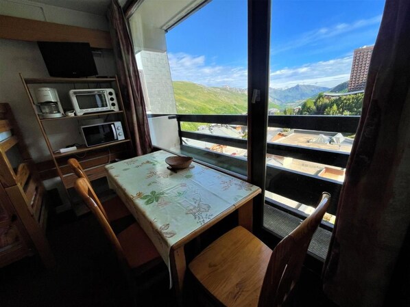 A small dining area with a table and chairs, a microwave, a coffee maker, and a view of a mountainous landscape.