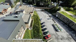 An aerial view of a parking lot with several cars, a bus, and a building with a sloped roof. - 10m from ski slopes, 6th floor, view valley, balcony, tv, 18m², Les Menuires (Les Menuires)