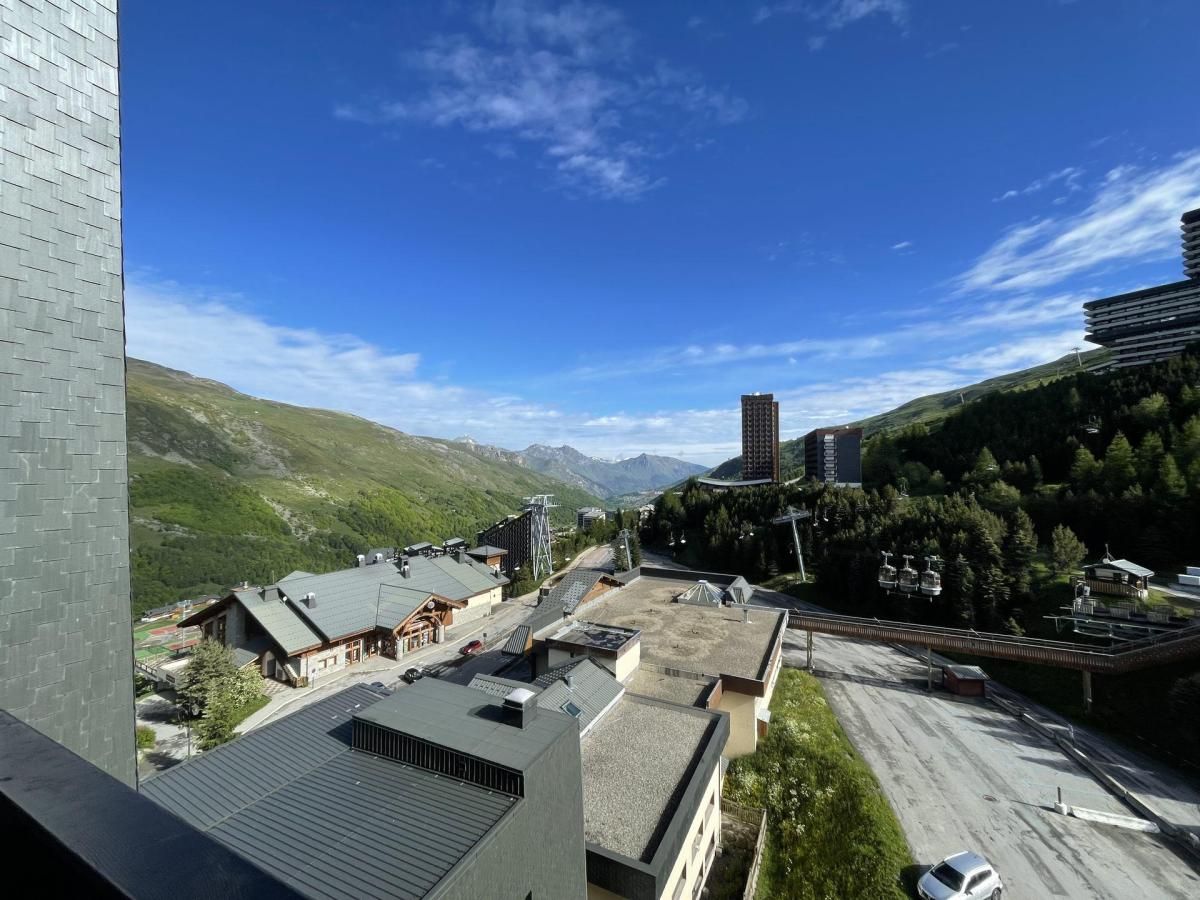 Ett bergigt landskap med byggnader, en skidlift och en klar himmel.
