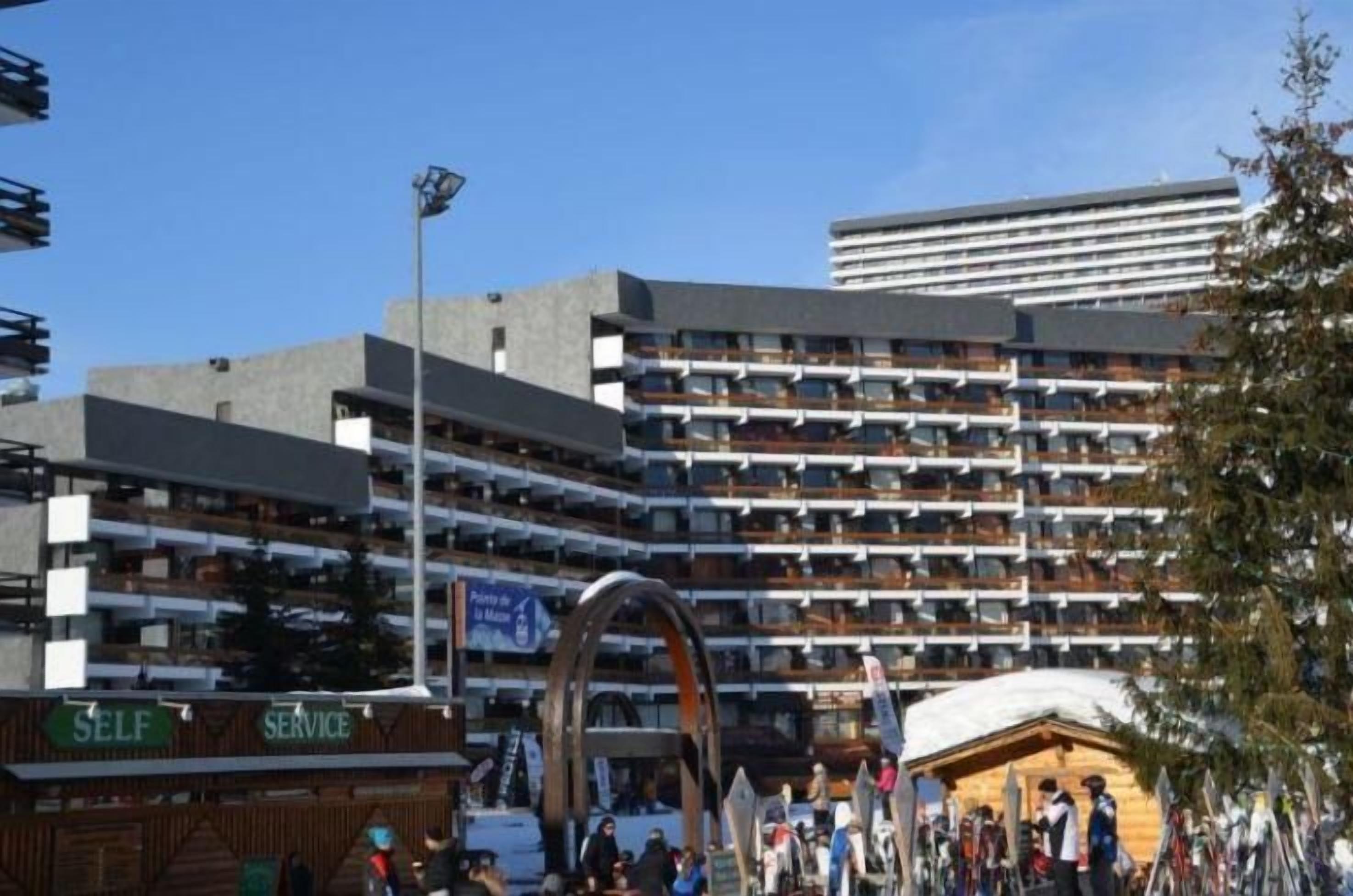 A multi-story hotel with balconies, a self-service area, and a ski lift area.