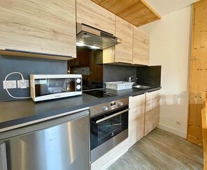 Une cuisine moderne dotée d’appareils électroménagers en acier inoxydable, d’armoires en bois et d’un plan de travail noir.