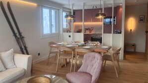 Una sala de estar moderna con comedor, muebles de madera y una cocina al fondo.
