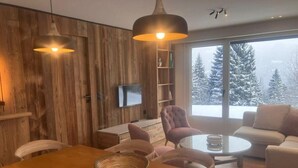 Una sala de estar acogedora con una pared de madera, una mesa de centro redonda y un sofá.
