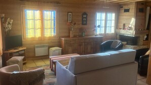 Una sala de estar acogedora con sofá, televisión, chimenea y paredes de madera.