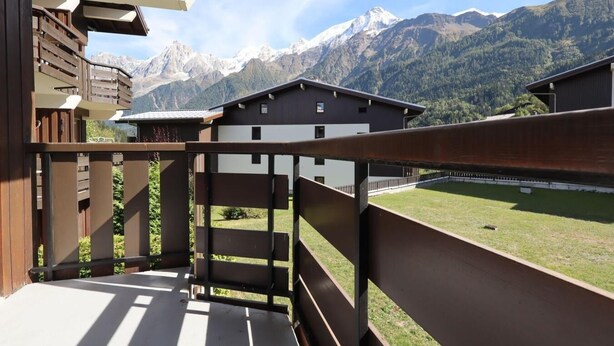 A balcony with a view of a mountain range and a building with a modern design.