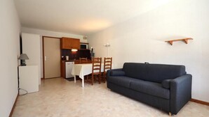 A compact living space with a kitchenette, a dining table, and a sofa.