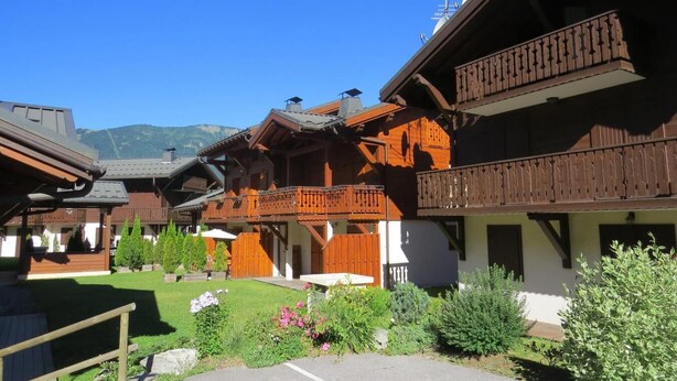 Ein traditionelles Chalet im Holzbau mit hölzernen Balkonen und einem gepflegten Garten.