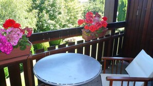 Un balcon avec une table ronde et deux chaises, entouré de rampes en bois.