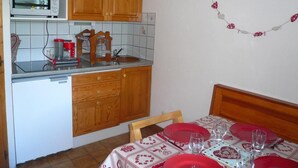 Una cucina compatta con mobili in legno, un forno a microonde e un'area pranzo con tavolo apparecchiato per due persone.