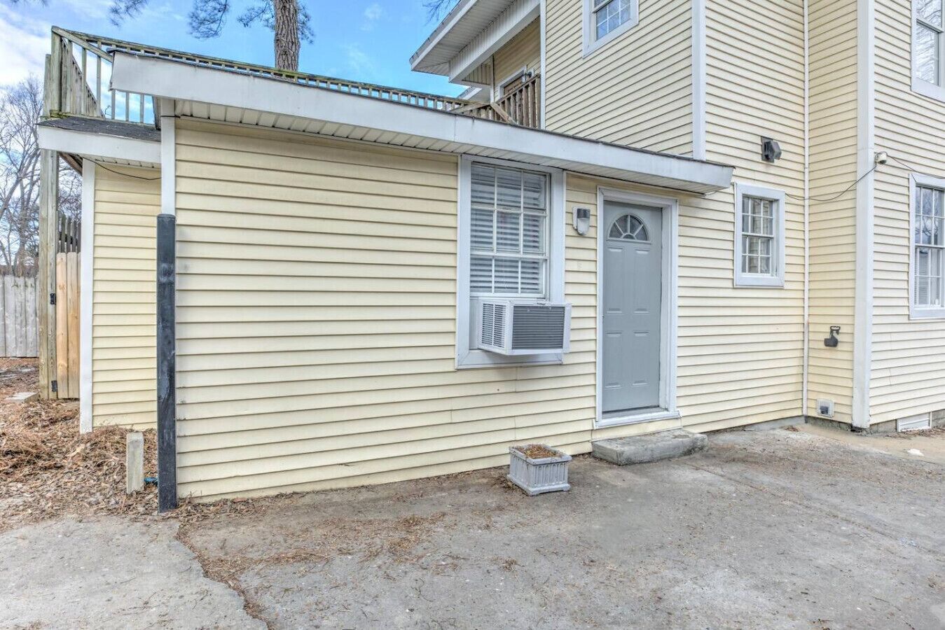 A single-story house with a front door, a small porch, and an air conditioning unit mounted on the wall.