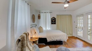 Un dormitorio con cama, mesita de noche, lámpara, alfombra y ventilador de techo.