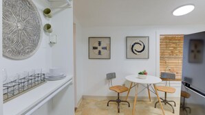 Una cocina moderna con encimera blanca, una mesa redonda con cuatro sillas y decoración en la pared.