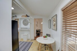 A compact kitchen with white cabinets, a black refrigerator, and a patterned rug.