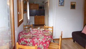 A dining area with a table set for four, wooden chairs, and a kitchen in the background. - 2nd floor, balcony, parking, tv, 21m², Les Houches (Les Houches)
