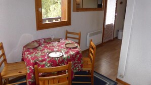 A dining area with a round table set for four, a window with a view of greenery, and a mirror on the wall. - 2nd floor, balcony, parking, tv, 21m², Les Houches (Les Houches)