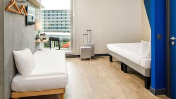 A hotel room with two beds, a desk with a chair, a suitcase, and a view of a building through the window.