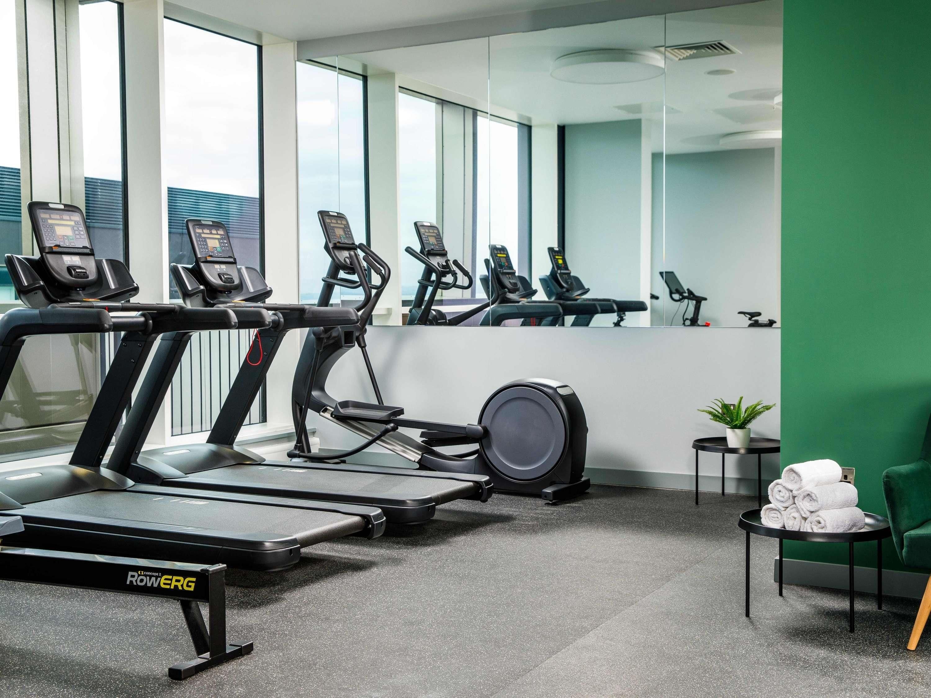 A gym with treadmills, a rowing machine, and a mirrored wall.