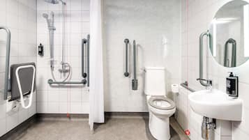Ein modernes Badezimmer mit Dusche, Toilette und Waschbecken, ausgestattet mit Haltegriffen und einer Handbrause.
