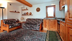A cozy living room with a sofa and a patterned rug, wooden cabinets, and a window with a view. - 300m from ski lifts, 1st floor, view mountain, balcony, tv, 40m², Les Houches (Les Houches)