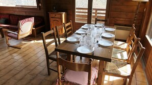 A wooden dining table set for four with chairs, a checkered tablecloth, and a window with a view of trees. - Chalet, view mountain, tv, 110m², Saint Gervais (Saint-Gervais-les-Bains)