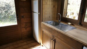 A wooden kitchen with a sink, a refrigerator, and a window with a view of greenery. - Chalet, view mountain, tv, 110m², Saint Gervais (Saint-Gervais-les-Bains)