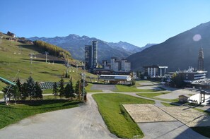 A ski resort with a ski lift, buildings, and mountains in the background.