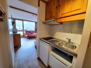 A compact kitchen with a sink, cabinets, and a window overlooking a cityscape.