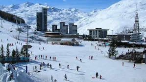 A ski resort with a ski lift, snow-covered slopes, and buildings in the background.