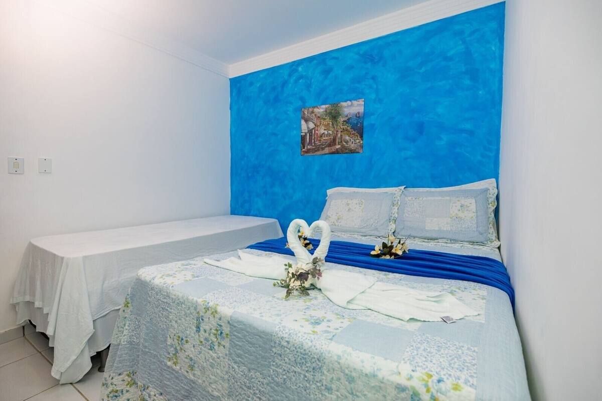 A hotel room with a single bed, a small table, and a blue accent wall.