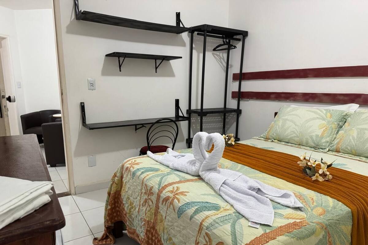 A hotel room with a bed, a desk, a chair, and a wardrobe.