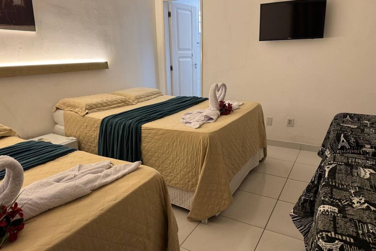 A hotel room with two beds, a flat-screen TV, a door, and a wall-mounted artwork.