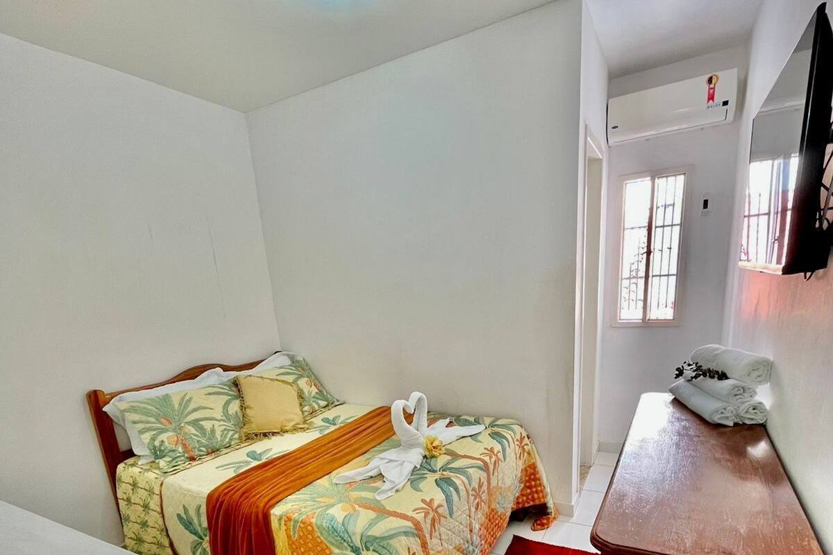 A small, clean room with two single beds, a wooden table, and a red rug.