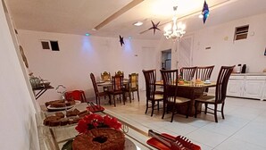 A dining area with a table set for a meal, a chandelier, and a ceiling fan. - Pousada Flor De Ponta Negra (Natal)