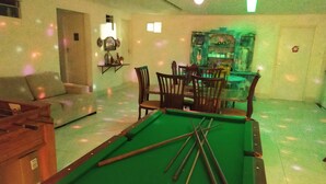 A pool table with cue sticks, a sofa, and a dining area with chairs and a table. - Pousada Flor De Ponta Negra (Natal)