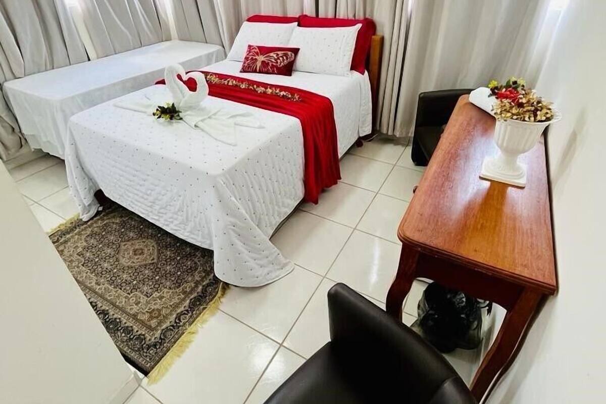 A hotel room with two beds, a small table, a chair, and a rug.