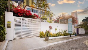 A gated entrance with a white wall, a metal gate, and a signboard. - Pousada Flor De Ponta Negra (Natal)