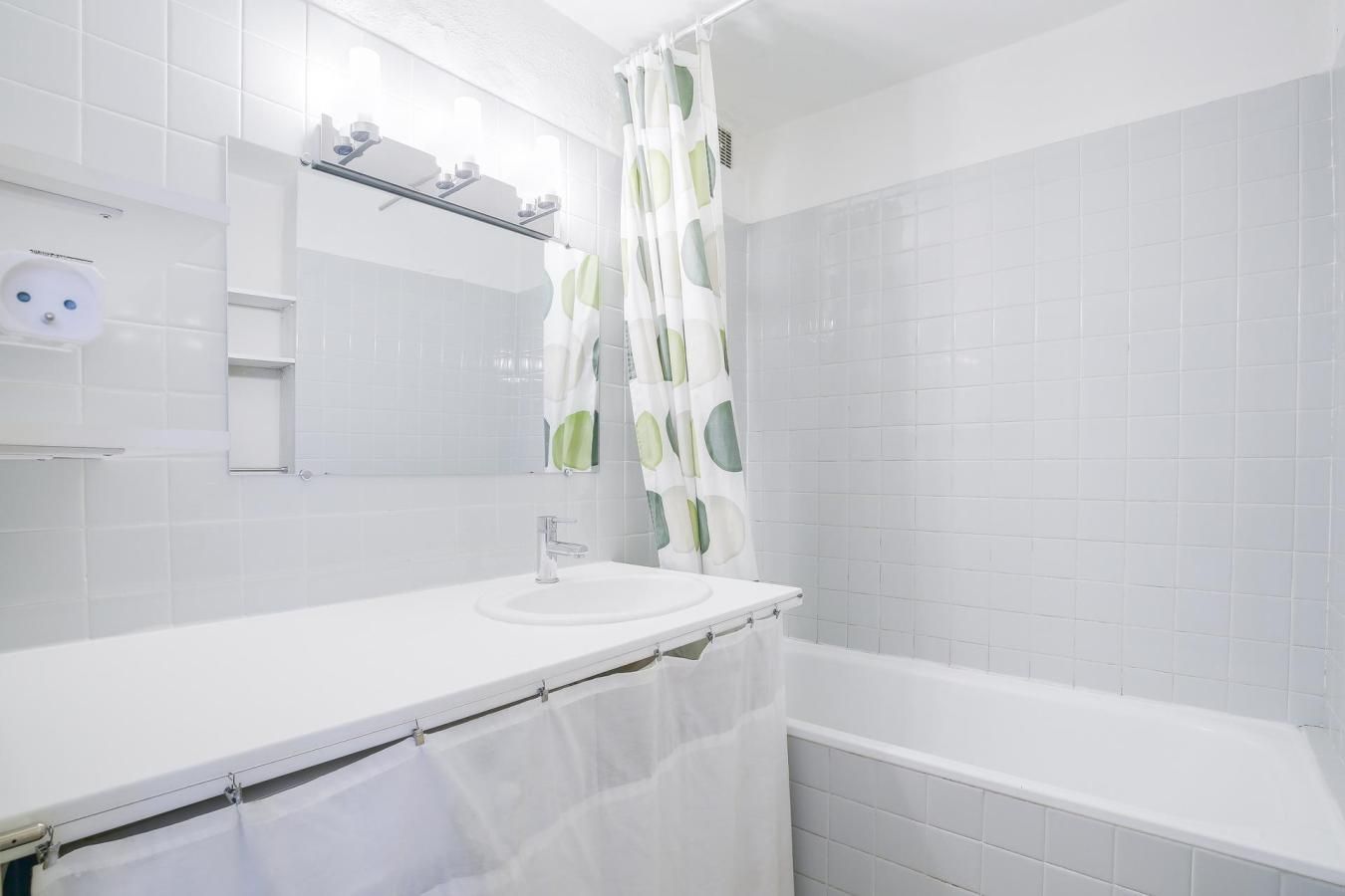Een badkamer met een witte wastafel, spiegel en douchegordijn.