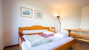 A neatly made bed with a wooden headboard, a bedside table, and a floor lamp. There are two framed pictures on the wall. - 150m from ski slopes, 5th floor, view mountain, balcony, parking, ski locker, 36m², Valfréjus (Valfréjus)